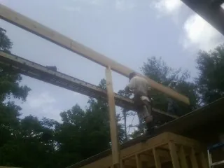 Carpenter setting a ridge beam over a new addition frame — Ice Dam Removal by Roofing Brothers in Whitesville