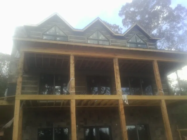 Dormers and porch framing on a large log home under construction — Roof Coating work by our crew in Whitesville