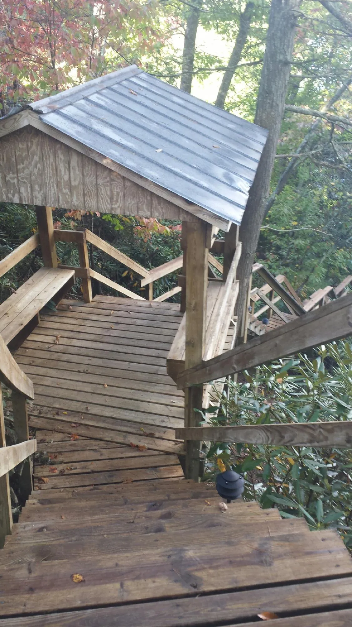 Metal roofed shelter over wooden steps on a wooded walkway — Skylight Repair & Installation work by our crew in Whitesville